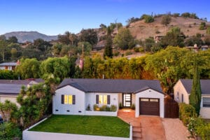 A single-story white house with a garage, surrounded by greenery, situated on Lucinda Ln in Santa Barbara's 93105 zip code area, with hills in the background.